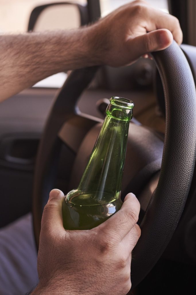 Homme buvant une bière au volant.