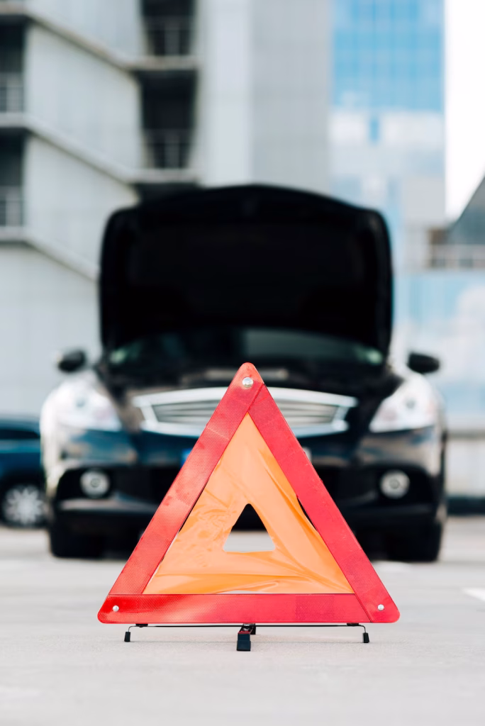 Voiture en panne avec un triangle de signalisation.