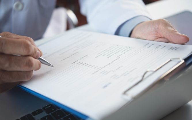 Un médecin remplit le formulaire d'un patient.
