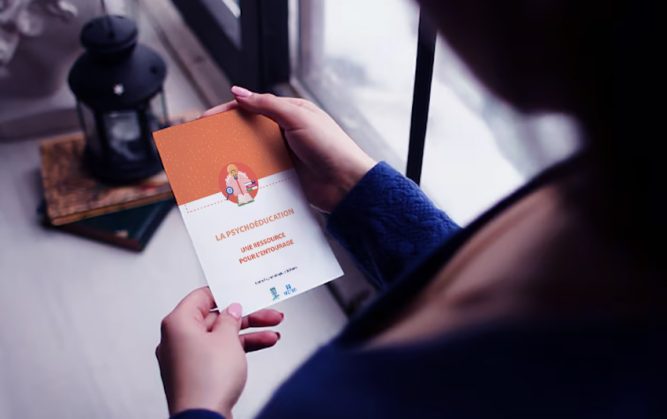 Femme tenant dans les mains un flyer sur la psychoéducation au CPN.