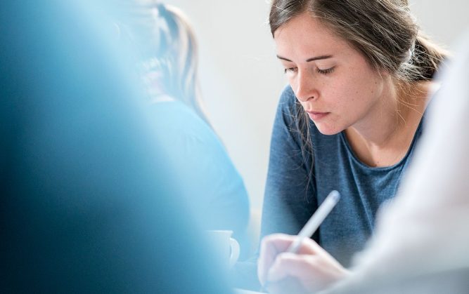 Réunion de plusieurs personnes, une femme est concentrée sur ses notes.