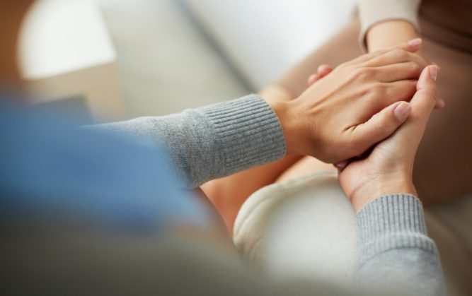Un soignant montre de la compassion envers un patient en lui tenant les mains.